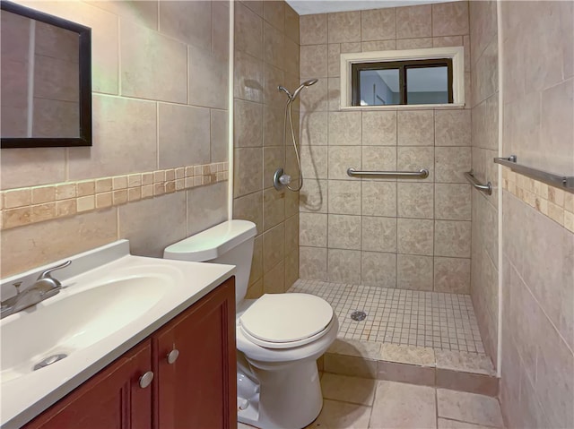 bathroom with tile walls, tile patterned floors, tiled shower, vanity, and toilet