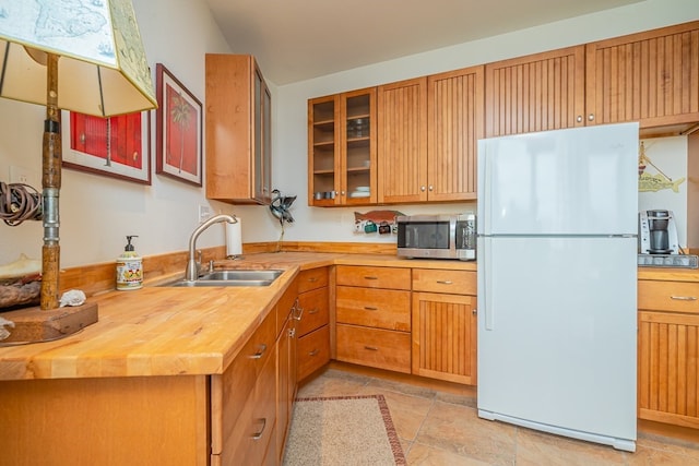 kitchen with wood counters, sink, and white refrigerator