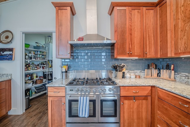 kitchen with double oven range, light stone counters, backsplash, dark hardwood / wood-style floors, and wall chimney exhaust hood