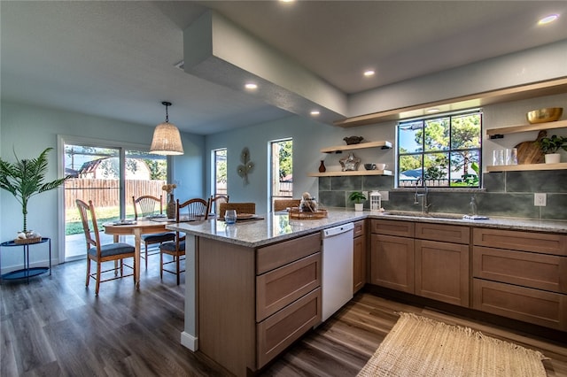 kitchen featuring dark wood-type flooring, light stone counters, white dishwasher, hanging light fixtures, and tasteful backsplash