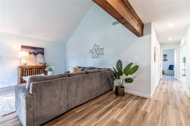 living room featuring light wood-type flooring and vaulted ceiling with beams