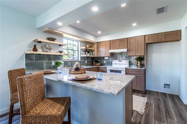 kitchen with light stone counters, white range with electric cooktop, dark hardwood / wood-style floors, decorative backsplash, and a kitchen breakfast bar