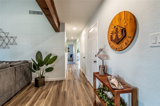 corridor featuring hardwood / wood-style floors and beamed ceiling