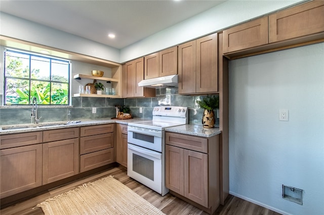 kitchen featuring white range with electric stovetop, light stone countertops, sink, decorative backsplash, and light hardwood / wood-style flooring