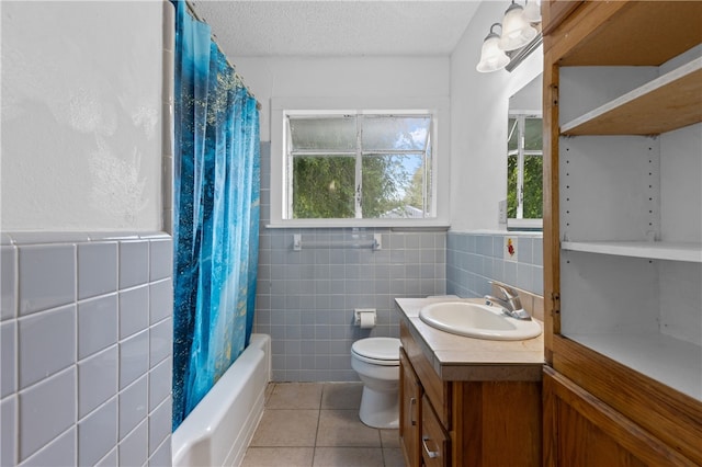 full bathroom featuring tile walls, vanity, a textured ceiling, tile patterned flooring, and toilet