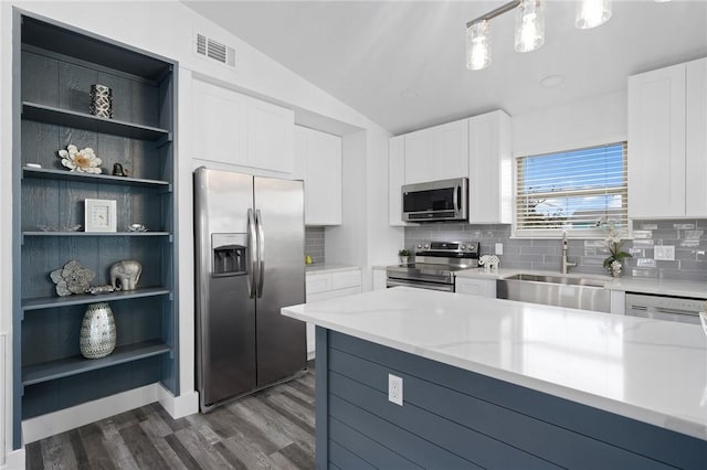 kitchen with vaulted ceiling, white cabinetry, stainless steel appliances, and decorative light fixtures