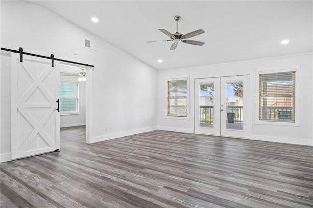 unfurnished living room with a barn door, ceiling fan, lofted ceiling, and hardwood / wood-style flooring