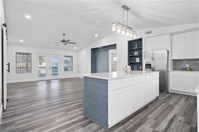 kitchen featuring stainless steel refrigerator with ice dispenser, backsplash, a center island, white cabinetry, and hanging light fixtures