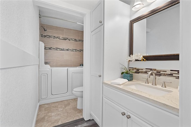 full bathroom featuring backsplash, vanity, washing machine and dryer, toilet, and tiled shower / bath