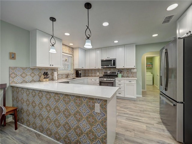 14350 Aquarius St, Corpus Christi, TX 78418 - kitchen with stainless steel appliances, arched walkways, a peninsula, light countertops, and white cabinets