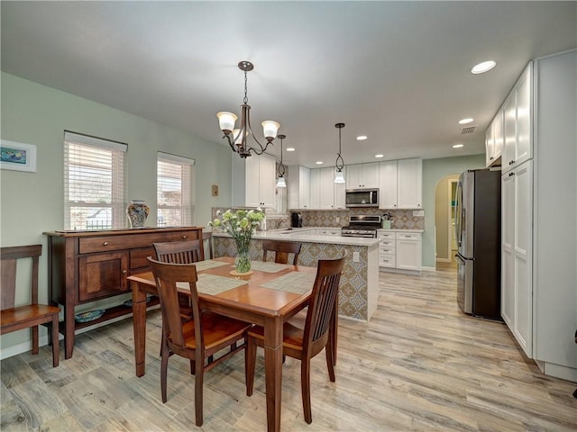 14350 Aquarius St, Corpus Christi, TX 78418 - dining room featuring light wood-type flooring, a chandelier, recessed lighting, and arched walkways