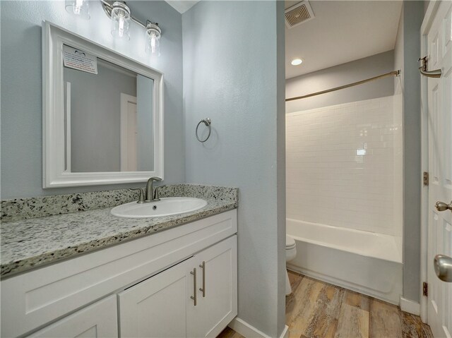 full bathroom with shower / bathing tub combination, hardwood / wood-style floors, vanity, and toilet