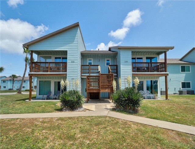 rear view of house with central air condition unit, a lawn, and a balcony