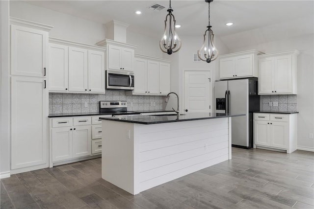 kitchen featuring white cabinets, decorative light fixtures, stainless steel appliances, and an island with sink