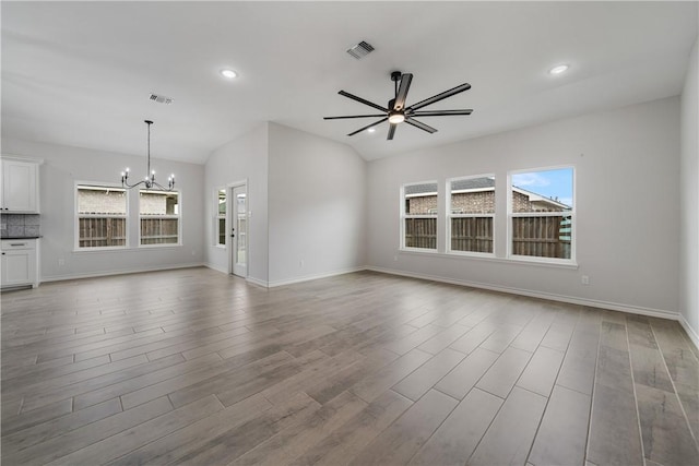 unfurnished living room featuring ceiling fan with notable chandelier and wood-type flooring