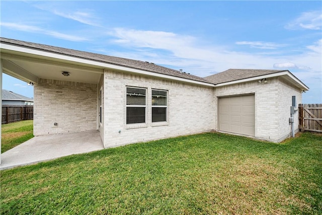 back of property featuring a lawn, a patio area, and a garage