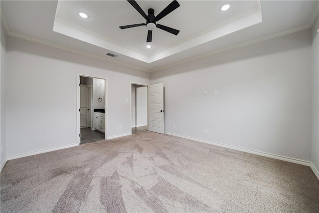 unfurnished bedroom with a raised ceiling, ensuite bath, and ceiling fan