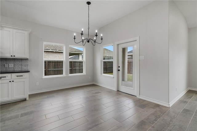 unfurnished dining area with a notable chandelier and vaulted ceiling