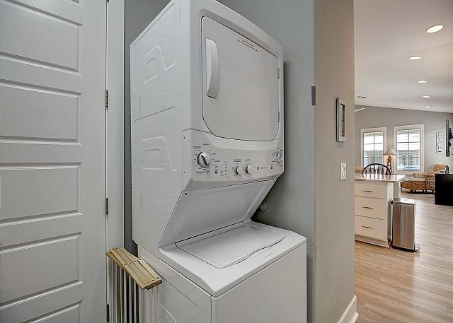 laundry room with stacked washer and dryer and light hardwood / wood-style floors