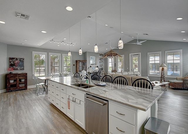 kitchen featuring dishwasher, sink, white cabinetry, hanging light fixtures, and a kitchen island with sink