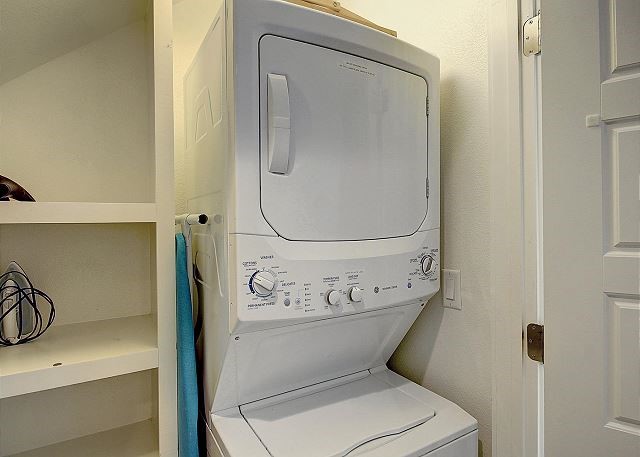 clothes washing area featuring stacked washer and clothes dryer