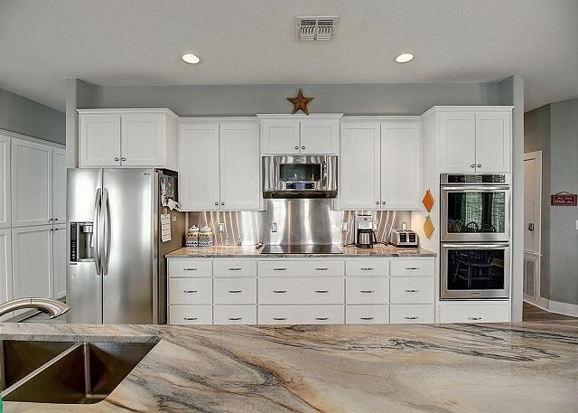 kitchen with stainless steel appliances, white cabinets, and light stone countertops