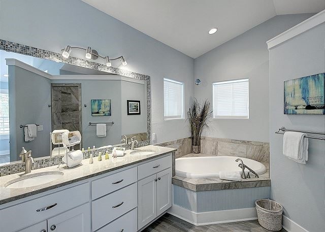 903 Banyan Beach Dr, Port Aransas, TX 78373 - bathroom featuring lofted ceiling, wood finished floors, a garden tub, double vanity, and a tile shower