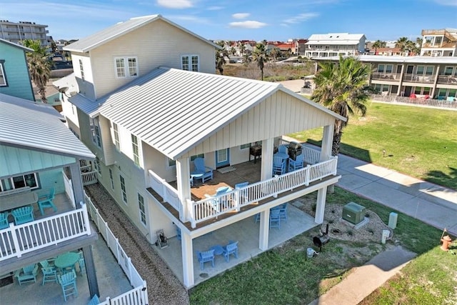 rear view of house featuring a balcony, a lawn, and a patio