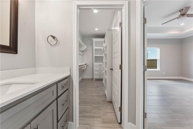 bathroom featuring ceiling fan, a raised ceiling, crown molding, and vanity