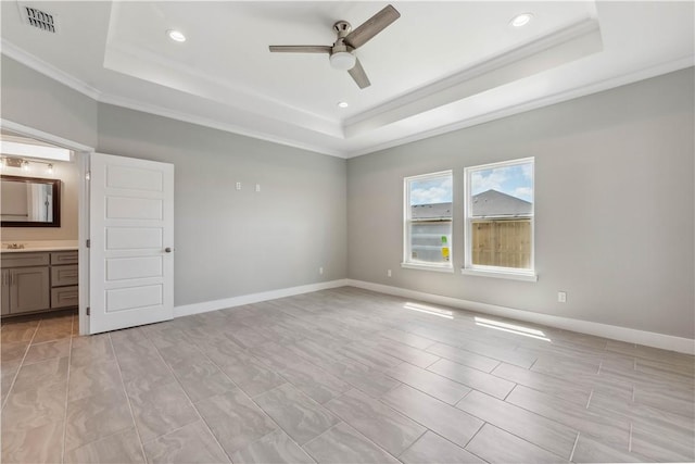 unfurnished bedroom with connected bathroom, ceiling fan, a raised ceiling, light tile patterned floors, and ornamental molding