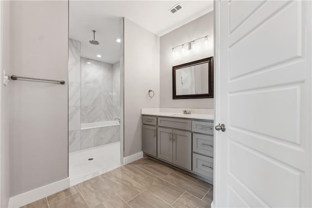 bathroom with a tile shower and vanity