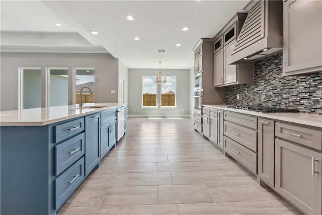 kitchen featuring custom exhaust hood, sink, appliances with stainless steel finishes, decorative light fixtures, and a chandelier