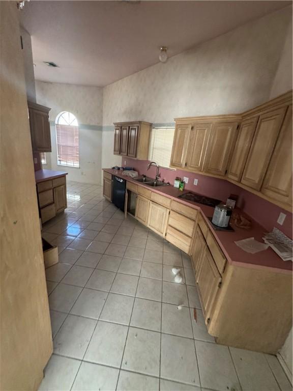 kitchen featuring black dishwasher, light tile patterned flooring, visible vents, and a sink