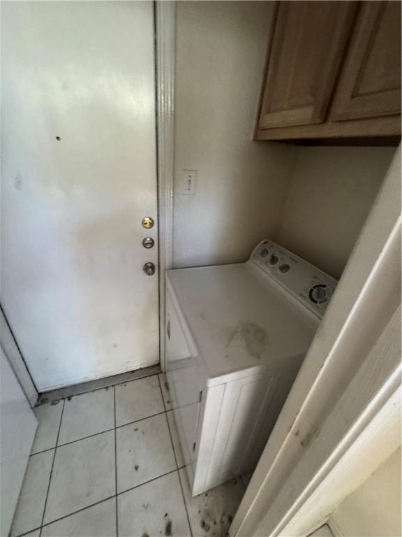 clothes washing area featuring cabinet space, washer / clothes dryer, and light tile patterned flooring