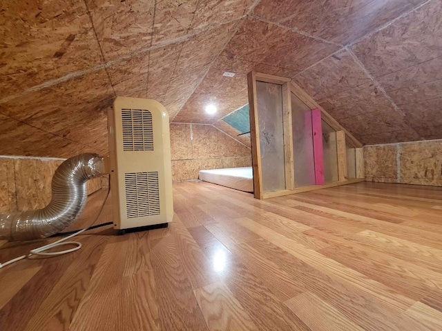 additional living space with hardwood / wood-style flooring, heating unit, and lofted ceiling