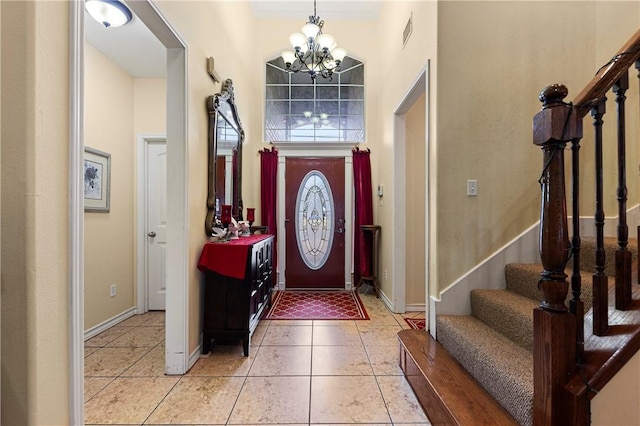 entrance foyer with a chandelier, a high ceiling, light tile patterned floors, and ornamental molding