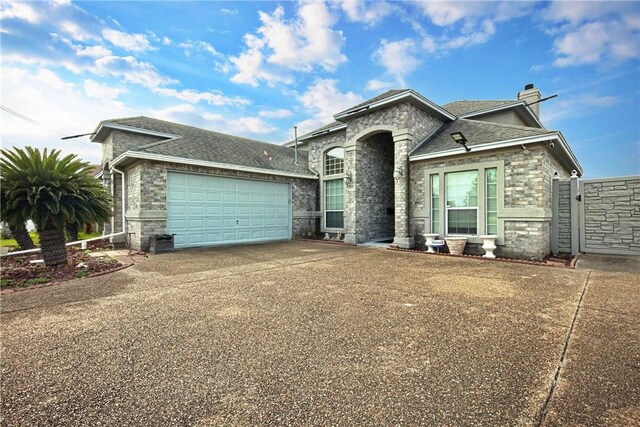 1725 Cliff Maus, Corpus Christi, TX 78416 - french provincial home featuring driveway, a garage, a chimney, a shingled roof, and stone siding