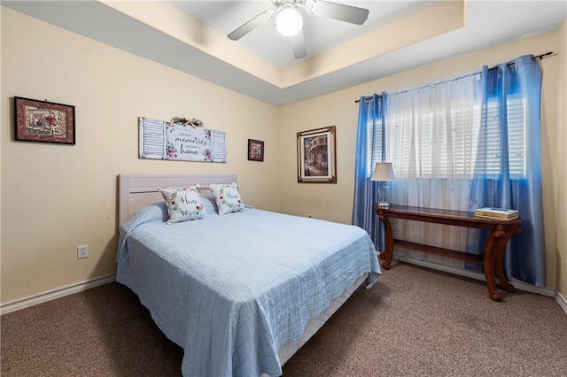 carpeted bedroom with ceiling fan and a raised ceiling