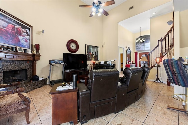 tiled living room with a high end fireplace, a high ceiling, and ceiling fan with notable chandelier