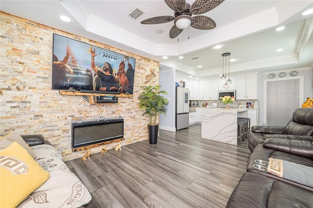 2774 Dallas Ave, Ingleside, TX 78362 - living area featuring a raised ceiling, a stone fireplace, ceiling fan, wood finished floors, and ornamental molding