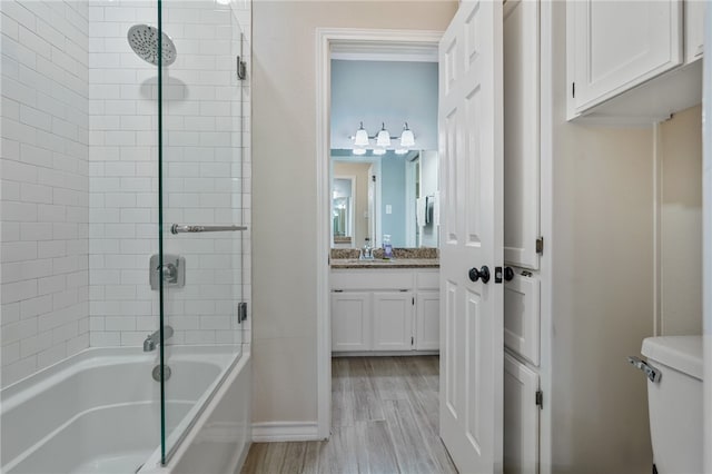 full bathroom featuring enclosed tub / shower combo, wood-type flooring, vanity, and toilet