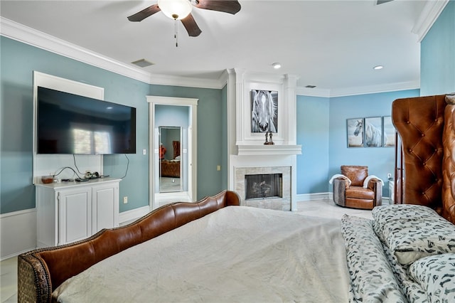 bedroom with a tiled fireplace, ceiling fan, and crown molding