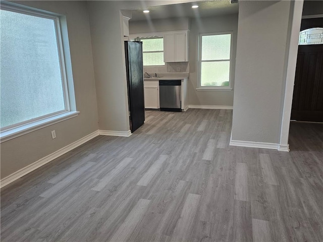 4134 Sierra St, Corpus Christi, TX 78410 - kitchen with stainless steel dishwasher, white cabinets, light wood finished floors, light countertops, and freestanding refrigerator
