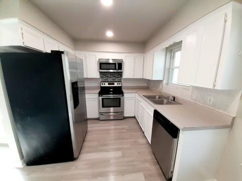 4134 Sierra St, Corpus Christi, TX 78410 - kitchen with stainless steel appliances, light wood-style floors, white cabinetry, tasteful backsplash, and light countertops