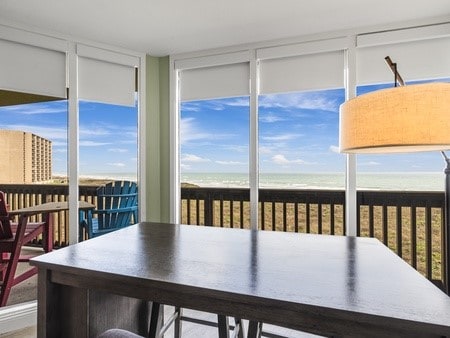 sunroom featuring plenty of natural light, a water view, and a beach view