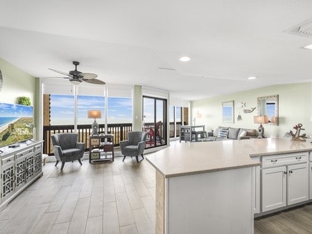 kitchen with white cabinets, ceiling fan, light hardwood / wood-style floors, and a kitchen island