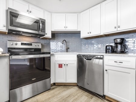 kitchen featuring sink, stainless steel appliances, light hardwood / wood-style flooring, backsplash, and white cabinets