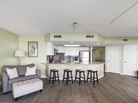 kitchen featuring kitchen peninsula, dark hardwood / wood-style flooring, a breakfast bar, stainless steel appliances, and white cabinets