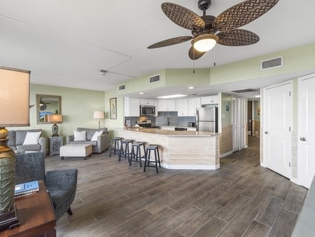 kitchen featuring kitchen peninsula, a kitchen bar, dark hardwood / wood-style flooring, stainless steel appliances, and white cabinetry