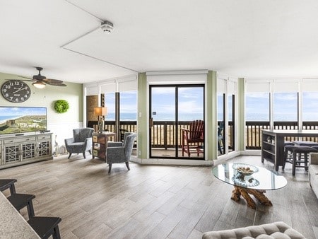 sunroom featuring ceiling fan and a water view